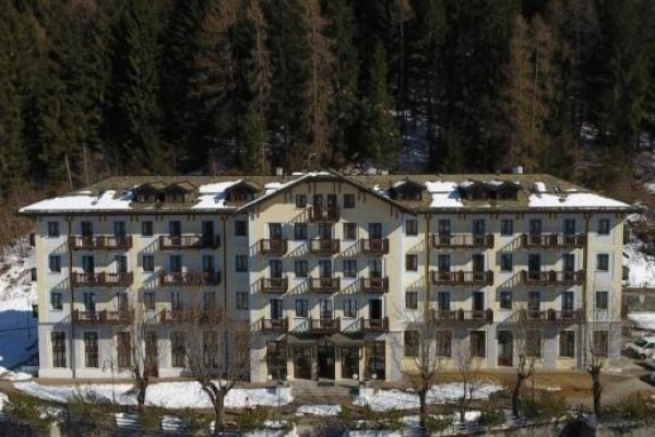 Budova hotelu se zasněženou střechou obklopená lesem.