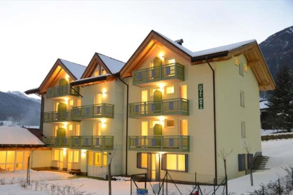 Hotel ve tvaru T s balkonem a zasněženou krajinou v pozadí.