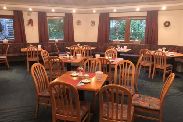 Restaurace s dřevěnými židlemi a prostřenými stoly.