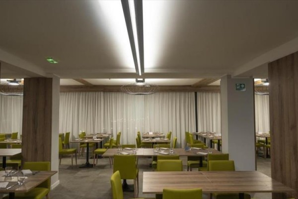 Restaurace s dřevěnými stoly a židlemi s olivově zelenými sedáky.