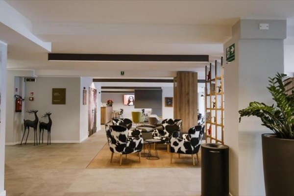 Moderní hotelová lobby s černobílými vzorovanými křesly a rostlinami.