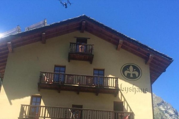 Budova s dřevěnými balkony a logem na stěně.