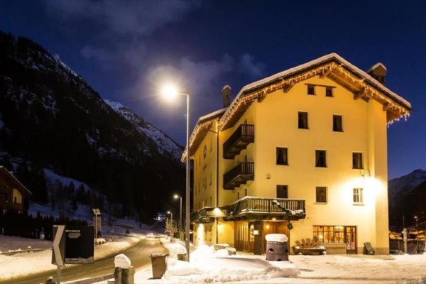 Zasněžený horský hotel osvětlený pouliční lampou v noci.