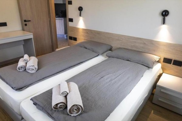 Moderní kuchyňská linka se dřevěnými skříňkami, světlem pod horními skříňkami a spotřebiči.