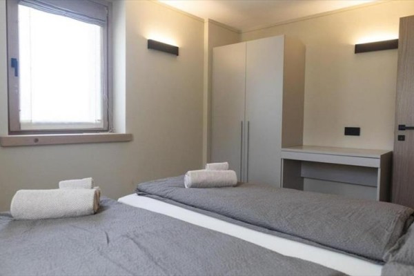 Moderní koupelna s toaletou, bidetem a umyvadlem na tmavých dlaždicích.