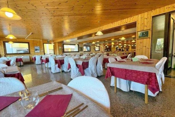Prostorná restaurace se stoly s bílým a červeným ubrusem.