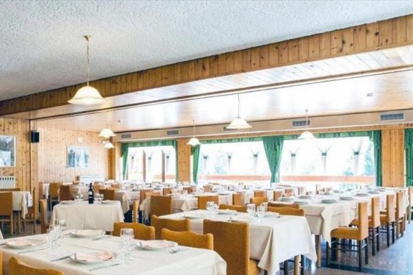 Restaurace s dřevěným obložením, prostřenými stoly a závěsy u oken.
