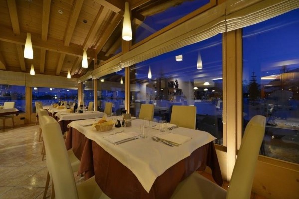Elegantní restaurace s bílými ubrusy a dřevěným interiérem za soumraku.  