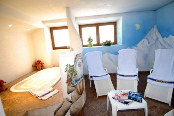 Relaxační místnost se třemi lehátky, stolkem s časopisy a vířivkou, dekorovaná nástěnnou malbou hor.